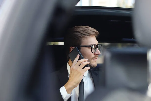 Nachdenklicher selbstbewusster Geschäftsmann, der im Auto telefoniert. — Stockfoto