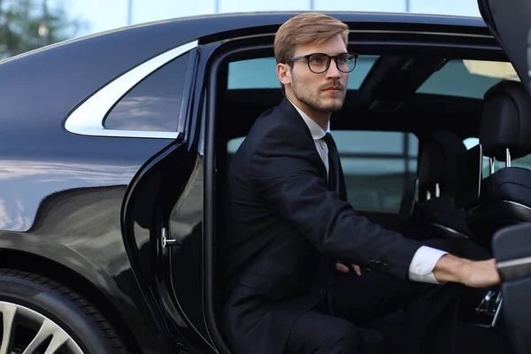 ハンサムな真面目な若いビジネスマンは、彼の快適な新しい車に座って、オフィスに行く. — ストック写真