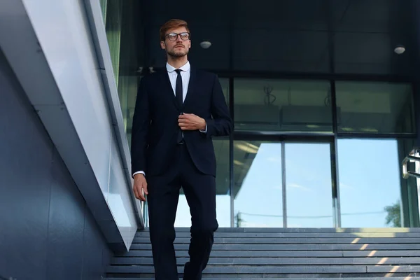 Joven empresario exitoso bajando las escaleras fuera del edificio de oficinas . — Foto de Stock