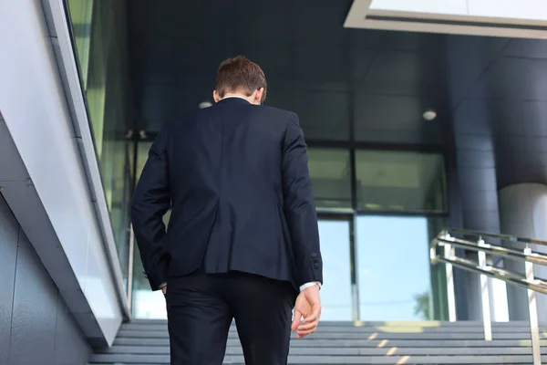 Elegante empresário de sucesso sobe as escadas do prédio de escritórios . — Fotografia de Stock