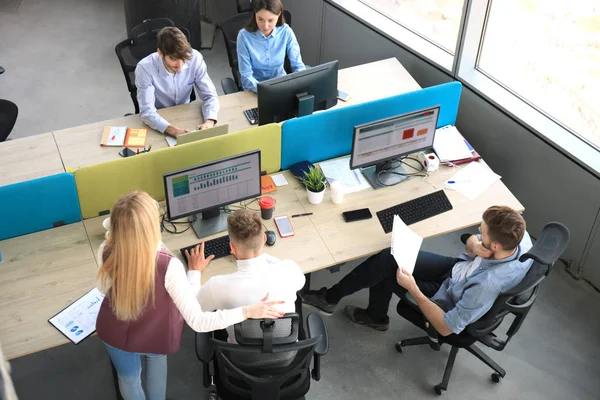 Vista superior de los jóvenes colegas modernos en ropa casual inteligente trabajando juntos mientras pasan tiempo en la oficina . —  Fotos de Stock