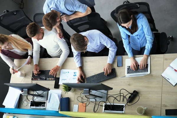 Вид молодых современных коллег в умной повседневной одежде, работающих вместе, проводя время в офисе . — стоковое фото