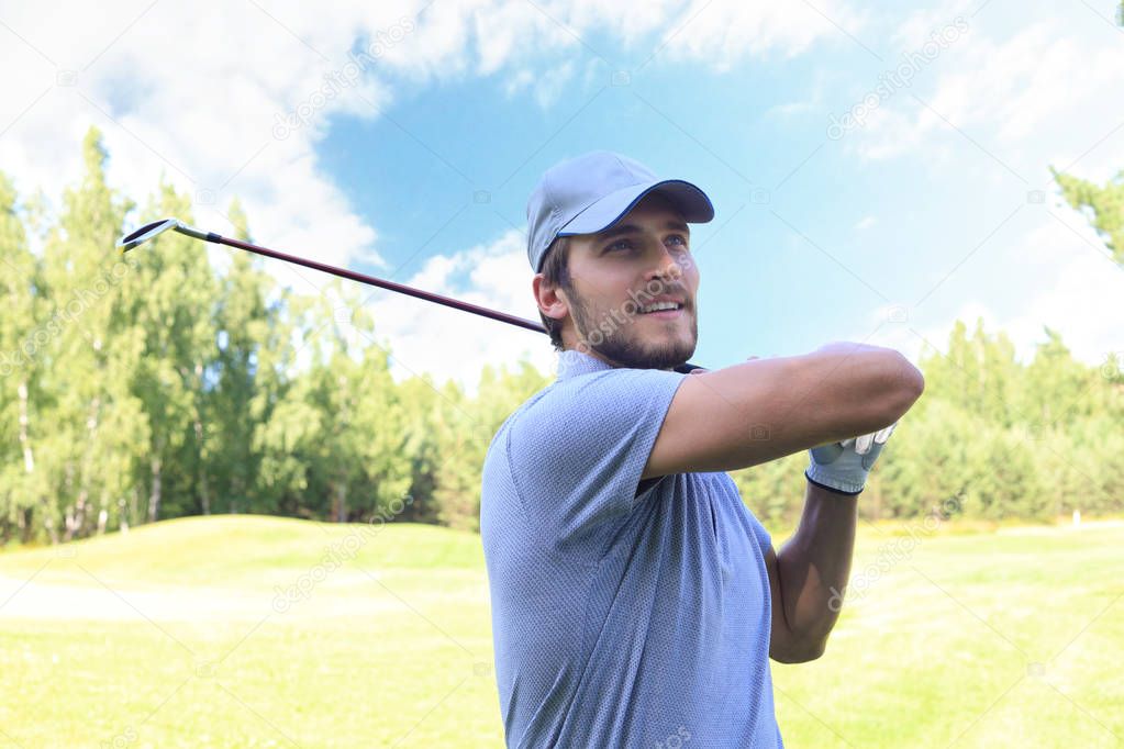 Golfer hitting golf shot with club on course while on summer vacation.