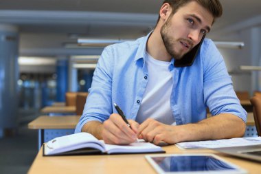 İş adamı ofisteki cep telefonunu kullanıyor..