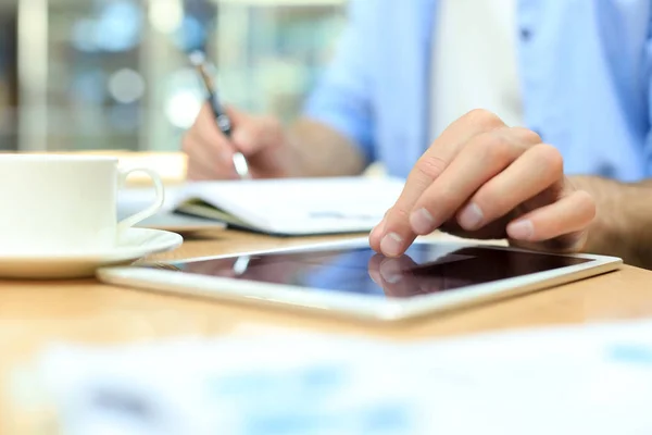 Homem escrevendo plano de trabalho com caneta no caderno de papel, navegando na internet no tablet digital na mesa de escritório . — Fotografia de Stock