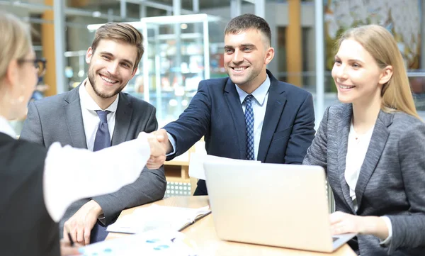 Welkom bij ons team. Jonge moderne zakenlieden schudden de handen terwijl ze werken in het creatieve kantoor. — Stockfoto