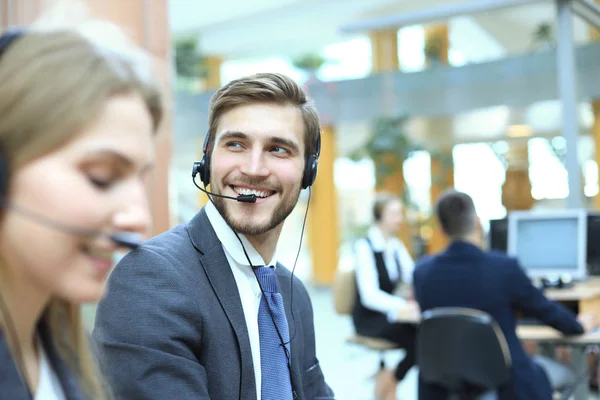 Porträt eines Callcenter-Mitarbeiters in Begleitung seines Teams. Lächelnder Kundenbetreuer bei der Arbeit. — Stockfoto