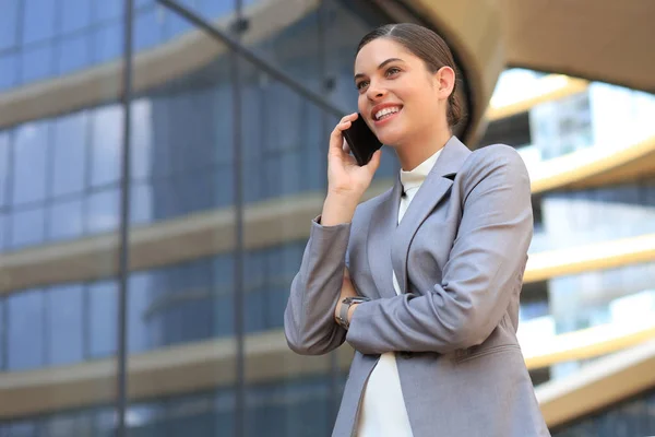 Portrait de femme d'affaires souriante élégante en vêtements à la mode appelant sur téléphone mobile près du bureau. — Photo