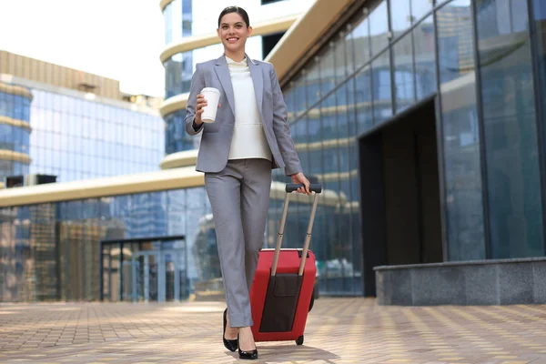 Portrait of successful business woman traveling with case at airport. Beautiful stylish female travel with luggage.