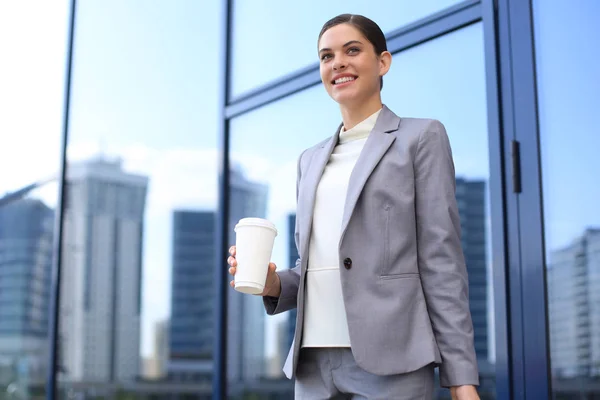 Retrato de una exitosa mujer de negocios que va a trabajar con café caminando cerca del edificio de oficinas en la calle de la ciudad. — Foto de Stock
