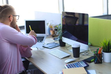 Ofiste otururken akıllı telefonda konuşurken gömlek iyi görünümlü genç adam.