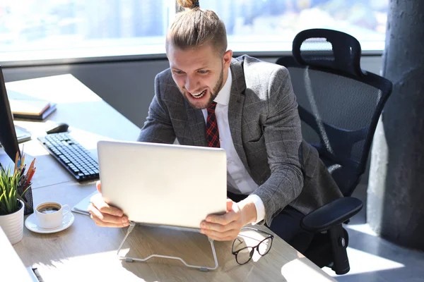 Empresario en traje completo con la boca abierta grita algo a un lado y sostiene el portátil en sus manos . — Foto de Stock