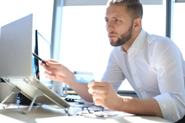 Joven hombre de negocios moderno analizando datos utilizando el ordenador portátil mientras trabaja en la oficina . — Foto de Stock