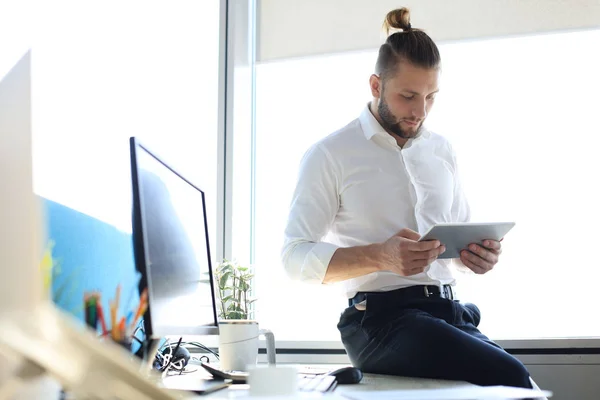 Młody nowoczesny biznesmen pracujący przy użyciu cyfrowego tabletu siedzącego w biurze. — Zdjęcie stockowe