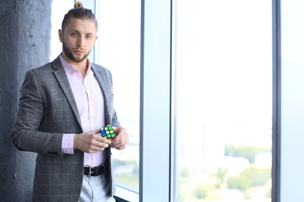 Bonito arquiteto masculino vestindo roupas casuais segurando Cubo de Rubik . — Fotografia de Stock