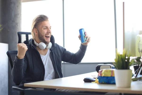 Portrait of ecstatic gamer guy in headphones screaming and rejoicing while playing video games on computer.