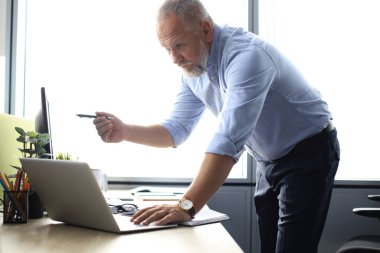 Zarif olgun işadamı ofiste çalışırken verileri analiz.