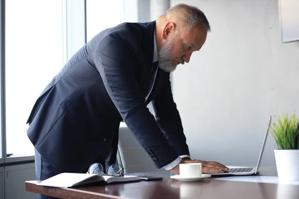 Элегантный зрелый бизнесмен анализирует данные во время работы в офисе . — стоковое фото