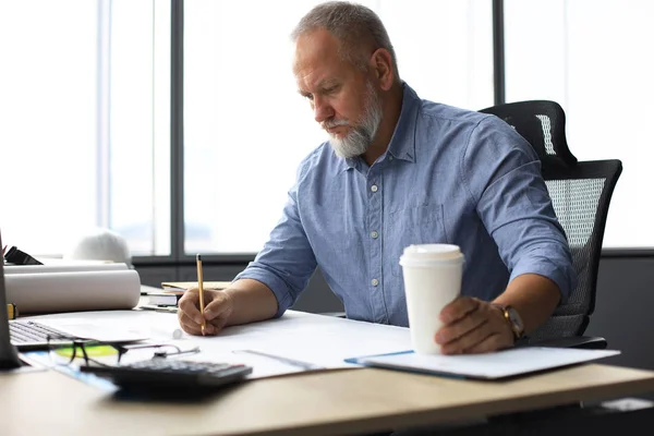 Snygg mogen arkitekt ritar något när han arbetar på kontoret. — Stockfoto