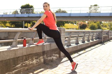 Spor elbiseli güzel bir kadın dışarıda dikilirken esniyor..