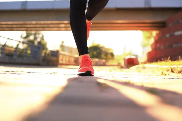 Close-up van jonge vrouwen in sportschoenen joggen tijdens het sporten buitenshuis. — Stockfoto