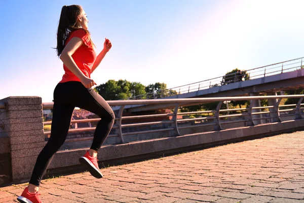 Foto van de moderne jonge vrouw in sportkleding springen tijdens het sporten buitenshuis. — Stockfoto