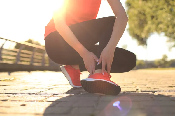 Sport woman - runner holding painful sprained ankle in pain. Female athlete with joint or muscle soreness and problem feeling ache in her lower body. — Stock Photo, Image