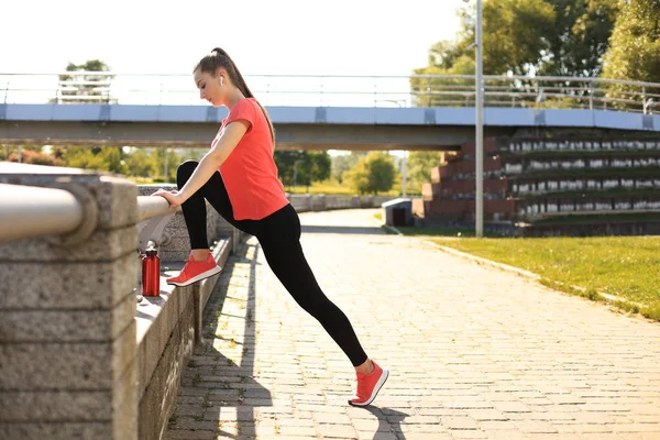 Mooie jonge vrouw in sport kleding stretching terwijl staan buiten. — Stockfoto