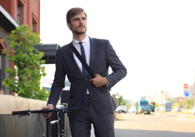 Şehirde sokakta bisikletle yürüyen pensive genç işadamı.