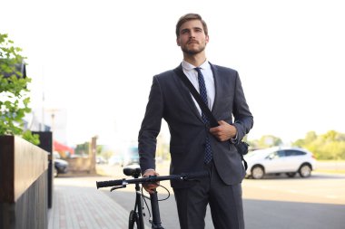 Şehirde sokakta bisikletle yürüyen pensive genç işadamı.