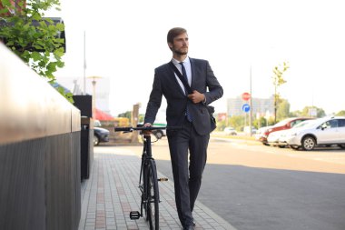 Şehirde sokakta bisikletle yürüyen pensive genç işadamı.