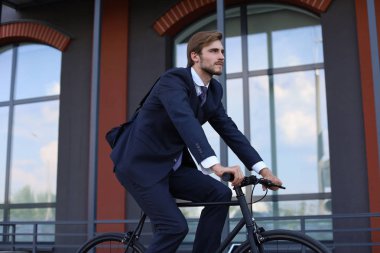 Sabah kentsel sokakta çalışmaya yakışıklı işadamı binicilik bisiklet.