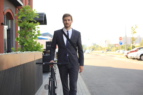 Jeune homme d'affaires pensif marchant à vélo dans la rue en ville . — Photo