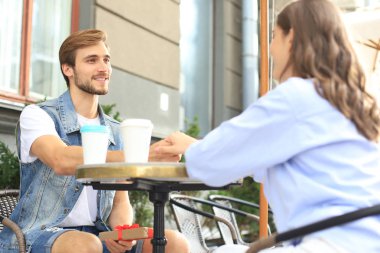 Gülümseyen genç adam kafede kız arkadaşı ile bir tarih sahip, mevcut kutu tutan.