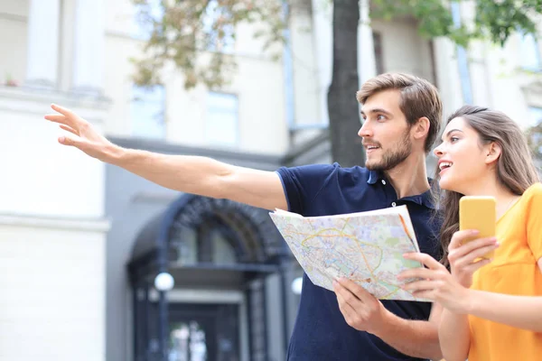 Image de jeune couple aimant mignon marchant à l'extérieur tout en tenant la carte . — Photo