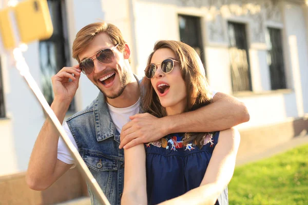 Hermosa pareja joven y encantadora caminando por las calles de la ciudad, abrazándose mientras se toma una selfie. — Foto de Stock