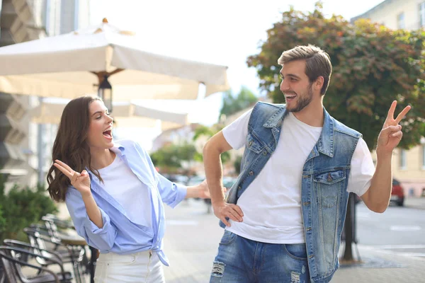 Hermosa pareja joven cogida de la mano y sonriendo mientras camina por la calle de la ciudad . — Foto de Stock