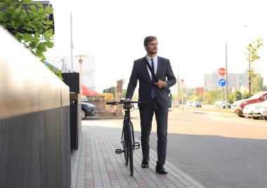 Şehirde sokakta bisikletle yürüyen pensive genç işadamı.