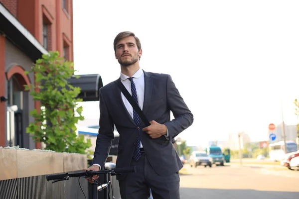 Jovem empresário pensativo andando de bicicleta na rua da cidade . — Fotografia de Stock