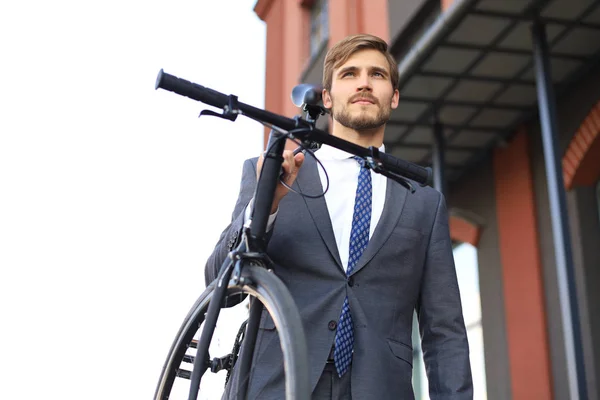 Όμορφος νεαρός επιχειρηματίας που κουβαλάει το ποδήλατό του στον ώμο ενώ περπατάει σε εξωτερικούς χώρους. — Φωτογραφία Αρχείου