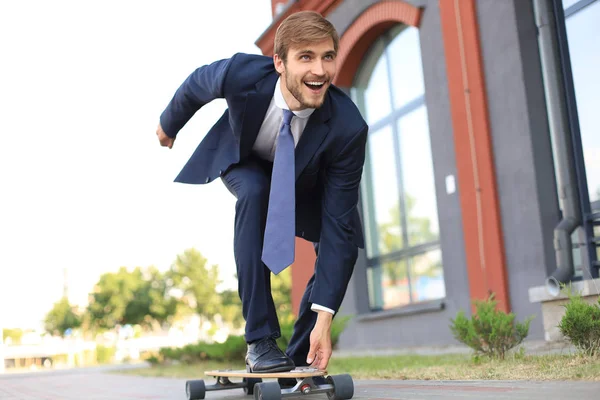 Jovem empresário confiante em terno de negócios em longboard apressando-se para seu escritório, na rua na cidade . — Fotografia de Stock