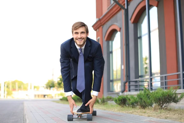 Zeker jonge zakenman in business man in pak longboard haast naar zijn kantoor, op de straat in de stad. — Stockfoto