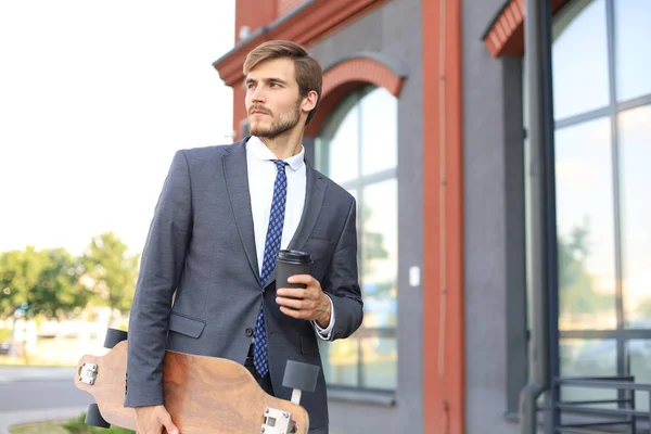 Zeker jonge zakenman lopen op de straat, met behulp van longboard. — Stockfoto