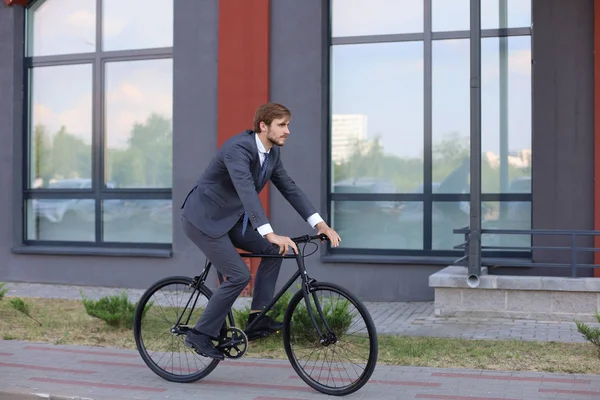 Όμορφος νεαρός επιχειρηματίας που καβαλάει το ποδήλατό του στην πόλη. Έννοια της οικολογικής μεταφοράς. — Φωτογραφία Αρχείου