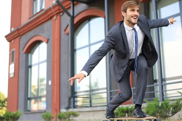 Αυτοπεποίθηση νεαρός επιχειρηματίας στην επιχείρηση κοστούμι σε longboard σπεύσει στο γραφείο του, στην οδό στην πόλη. — Φωτογραφία Αρχείου