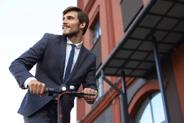 Takım elbiseli genç, iş toplantısında elektrikli scooter'a biniyor. Ekolojik ulaşım kavramı. — Stok fotoğraf