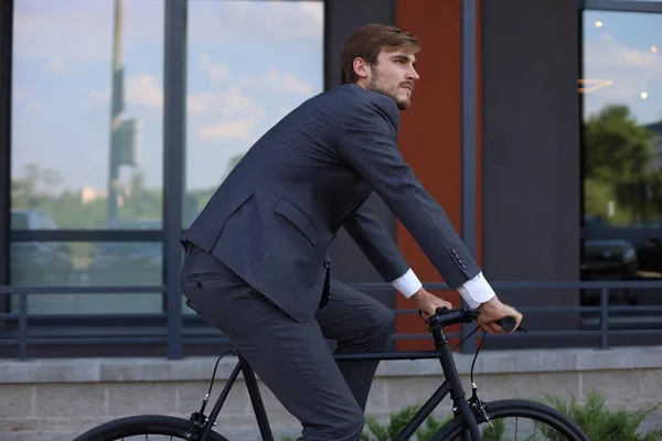 市内で自転車に乗っているハンサムな若いビジネスマン。エコロジー輸送の概念. — ストック写真