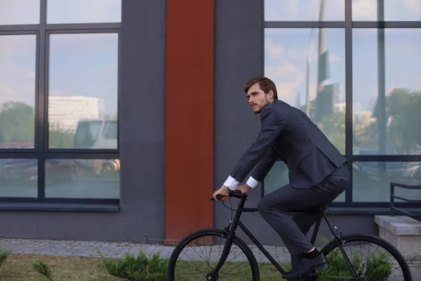 Bonito jovem empresário andando de bicicleta na cidade. Conceito de transporte ecológico . — Fotografia de Stock