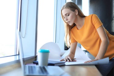 Güzel modern kadın yaratıcı ofiste çalışırken planı aşağı bir şey yazıyor