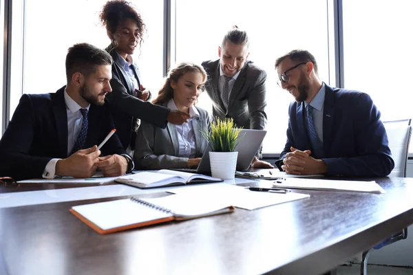 Groupe de jeunes gens modernes en tenue de cérémonie souriant et discutant de quelque chose tout en travaillant dans le bureau moderne — Photo